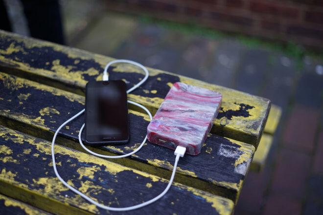 a pink marbled external charger connected to a phone on a table