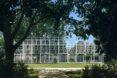 a trapezoid structure full of white cross beams and surrounded by greenery