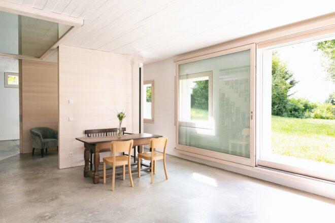 small dining table and wood chairs near wall of windows