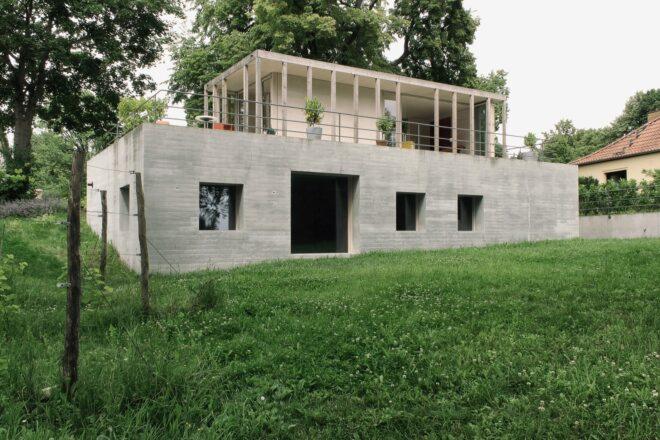 concrete home with wood pavilion on the roof