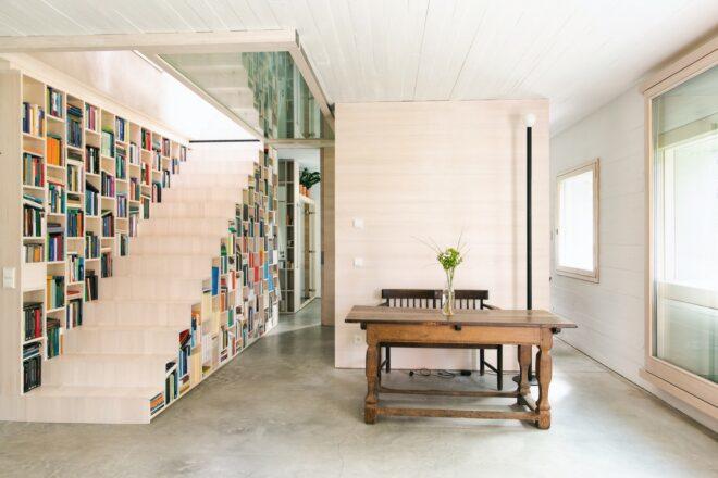 dining table next to stairs that double as a bookcase