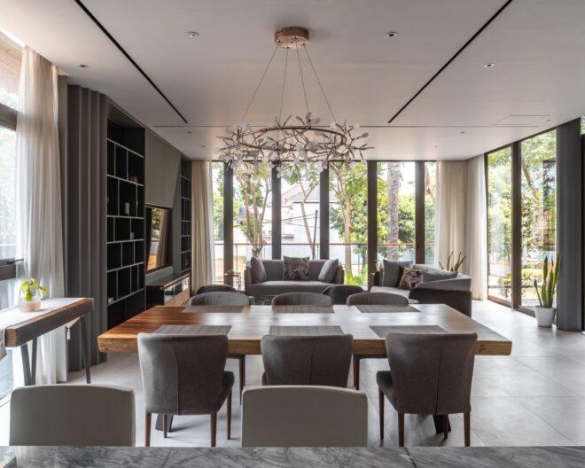 interior of a dining room with table and chairs, and a living room with TV and sofas in the background