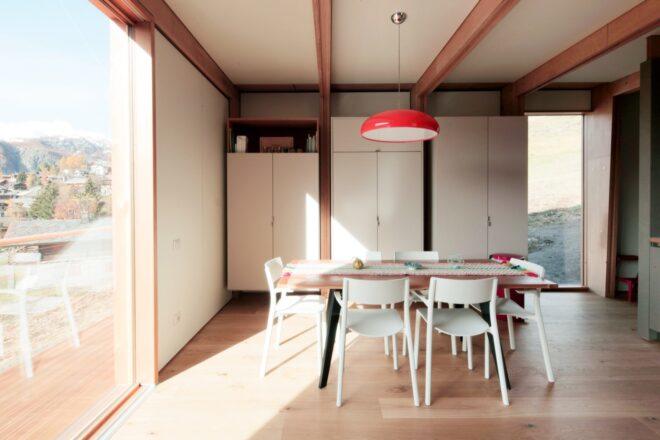 wood table and white chairs in room with glass wall and wood-beamed ceilings