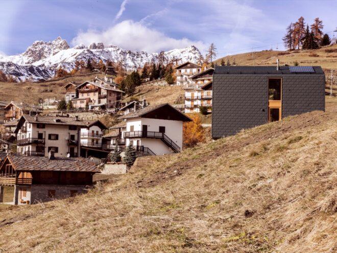 dark gray home on a hill with view of village in the valley