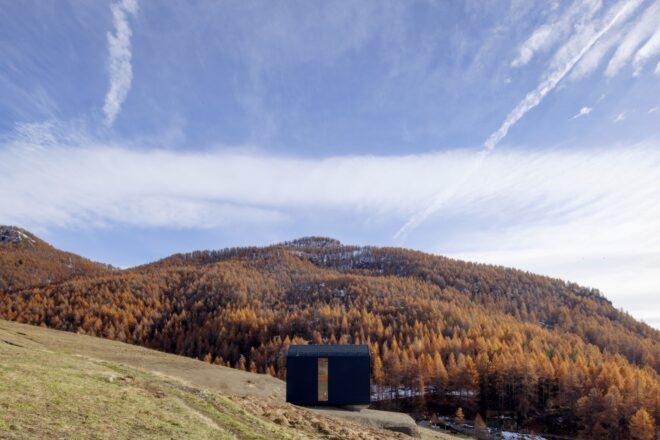 dark gray home on a hill with mountains in distance