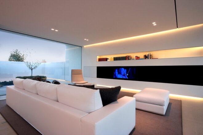 white sofa and white chairs facing a mounted TV on a white wall