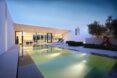 large swimming pool and lounge chairs outside a white villa