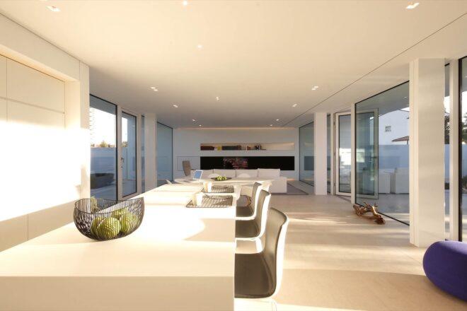 long white kitchen island with several dark chairs