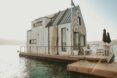 floating wood home with gabled roof and large patio