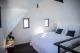 all-white bedroom with white bed and two small windows