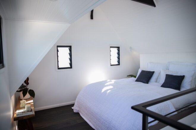 all-white bedroom with white bed and two small windows