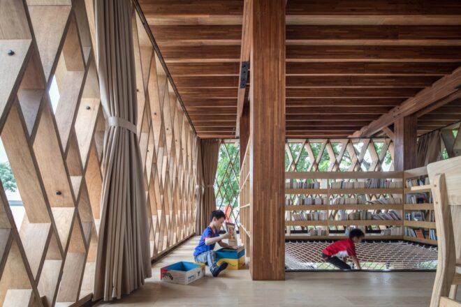 kids sitting inside a wood library with bookshelves