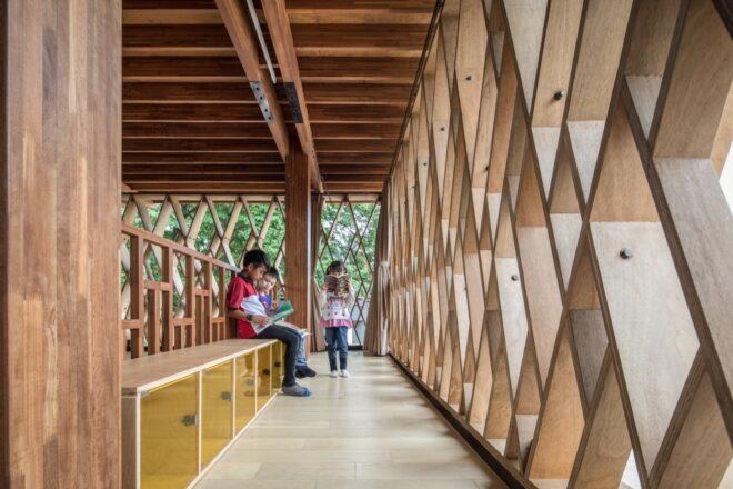 kids sitting on a bench and reading inside a wooden library