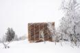 box-like wood cabin in snowy landscape