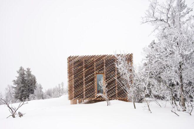 box-like wood cabin in snowy landscape