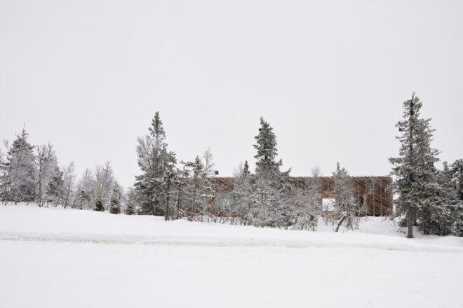 expansive, snowy landscape with cabin on the horizon
