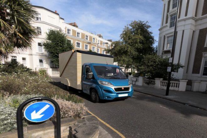 blue truck with wooden box driving on urban road
