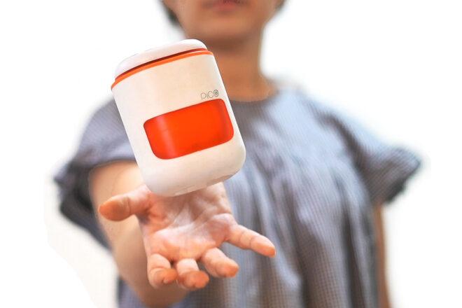 a person with a white and orange PICO pod hovering above their hand