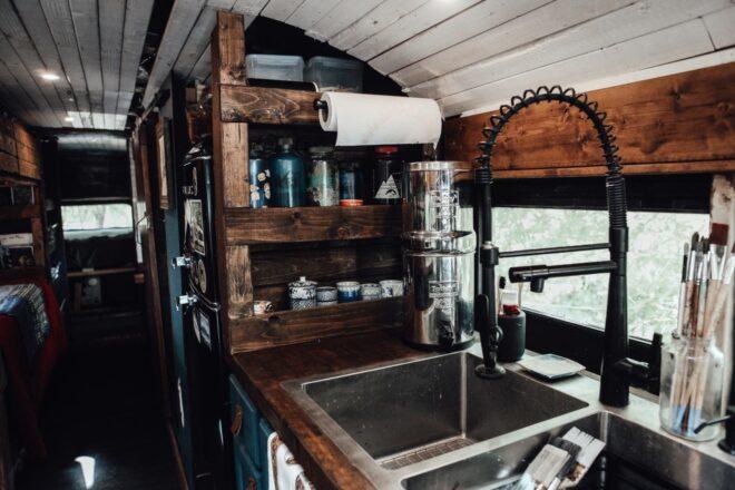 a kitchen with wooden shelving next to a large sink