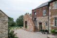home surrounded by partially destroyed brick walls