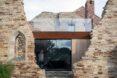 outdoor structure in ruins with modern glass structure in the middle of the ruins
