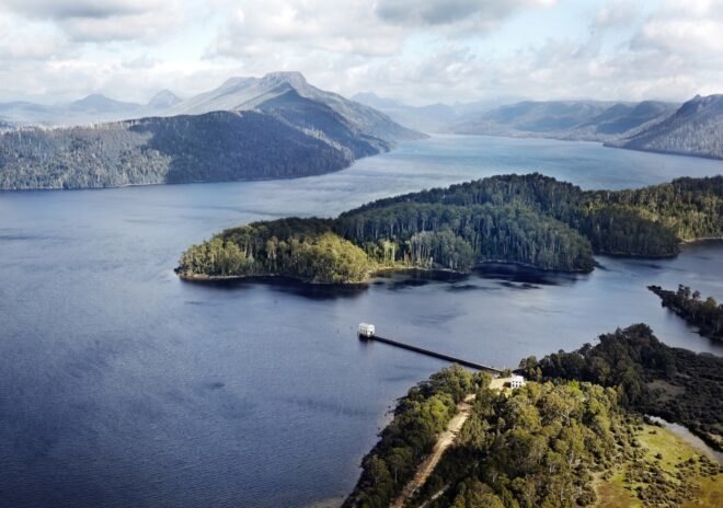 aerial view of long path leading to tan gabled building on a lake
