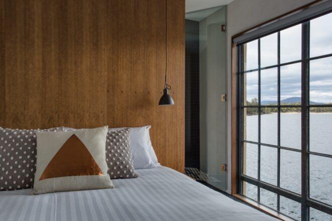 white bed with patterned pillows next to a large window