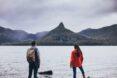 two people by a lake looking at a mountain