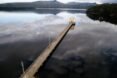 long wood path leading to tan gabled building on a lake