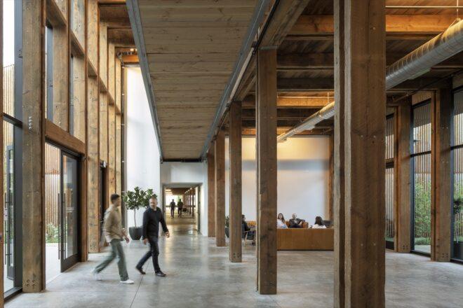 people walking into entrance with glass wall and wood support beams