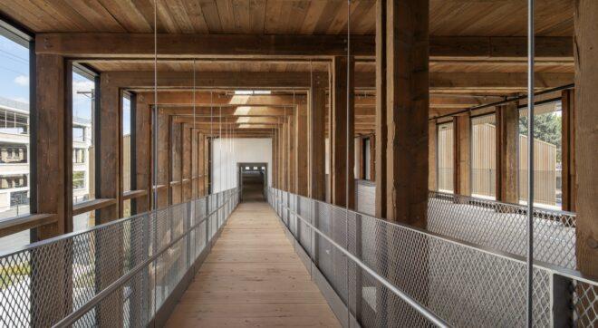long wood walkway leading to open doorway under a wood ceiling