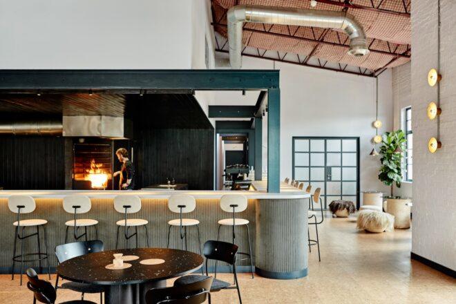the interior of a restaurant featuring tables, chairs and a bar area with stools