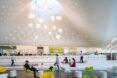 green, white and yellow chairs under a curvy ceiling with a round skylight