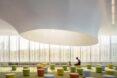 parent and child sitting on colorful stools in a glass building