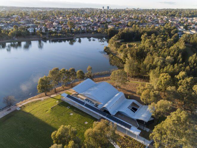 aerial view of lakeside community center with white wavy roof