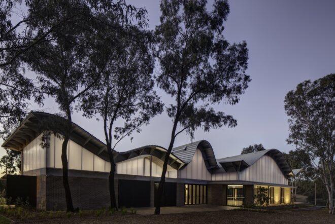 glass building with wavy roof at dusk