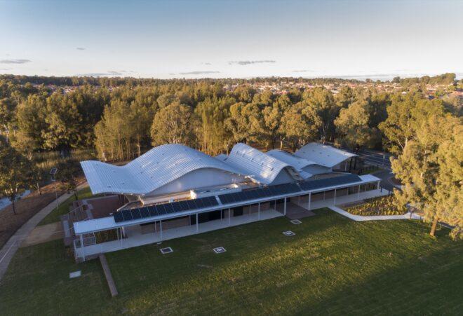 aerial view of white building with wavy roof and solar panels