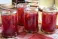 four cans of red jam flipped upside down on a red and white checkered cloth