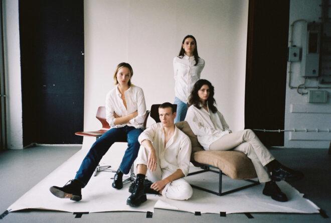 group of people sitting in chairs and wearing jeans and white collared shirts