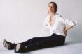 person sitting on floor wearing dark jeans and a white tailored shirt
