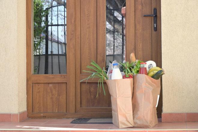 two paper bags full of groceries on a front porch