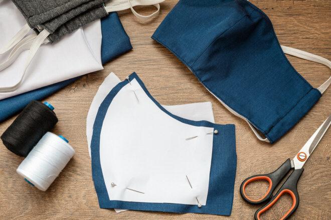 cloth cut into mask shapes near thread and scissors