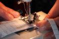 person using sewing machine to make fabric mask