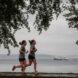 two people running beside waterfront with boats