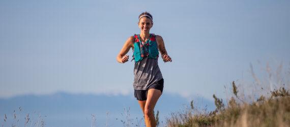 person running and smiling with ocean and mountains in background