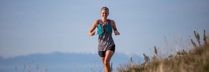 person running and smiling with ocean and mountains in background