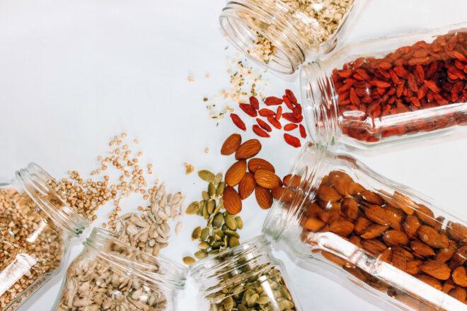 jars of seeds and nuts spilling onto white background