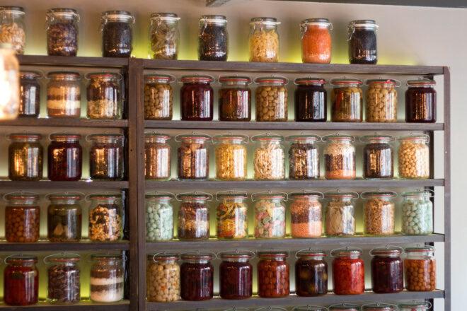 wood shelves of jarred flours, seeds, nuts and preserved produce