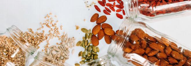 jars of seeds and nuts spilling onto white background