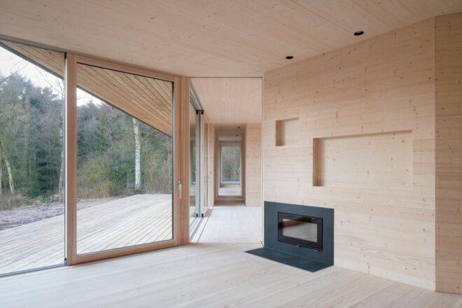 light wood-lined home with small fireplace and one glass wall